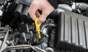 Mechanikas matuoja alyvos lygį automobilyje.